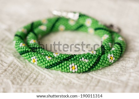 Necklace from beads with flower drawing on a textile background