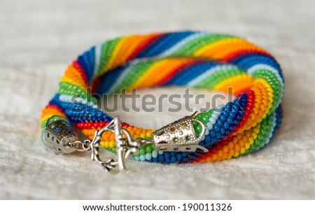 Necklace from beads of a rainbow colors on a textile background