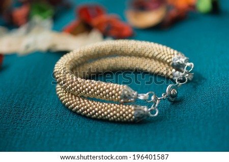 Knitted bracelet of gold color from beads