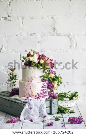 Sweet wedding cake with fresh flowers on wooden background