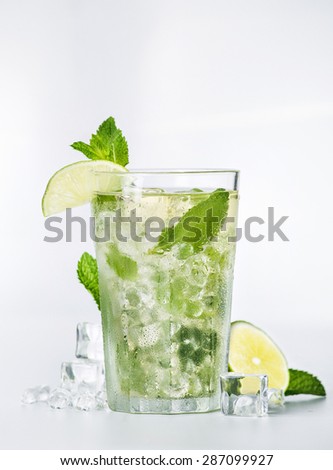 Fresh mojito cocktail with mint, lime and ice cubes on white background