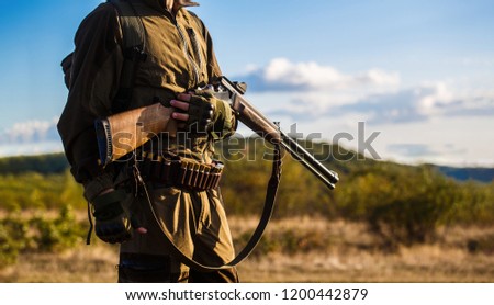 Hunter man. Hunting period, autumn season. Male with a gun. A hunter with a hunting gun and hunting form to hunt in an autumn forest. The man is on the hunt. Hunter with a backpack and a hunting gun.
