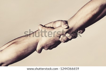 Rescue, helping gesture or hands. Strong hold. Close-up. Two hands, helping hand of a friend. Handshake, arms, friendship. Friendly handshake, friends greeting, teamwork, friendship.