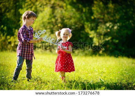 A little cute girl and a boy holding a plastic phrase \