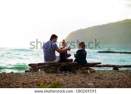 Back view of a father and his kids walking on the sea shore