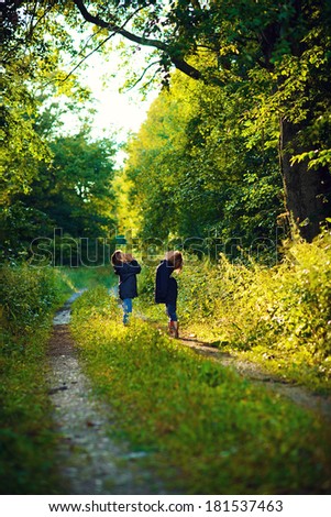 Two brothers having fun in the green wet forest after the rain on a sunny summer day
