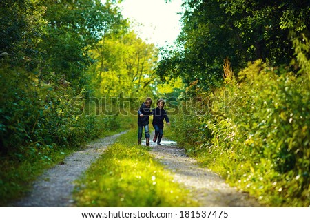 Two brothers running in the green wet forest after the rain on a sunny summer day