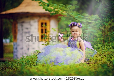 A little beautiful elf near the tiny house in the meadow on a sunny summer day