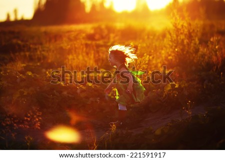 A little pretty girl in a green dress running after the rabbit on a sunny summer evening. Kids are playing