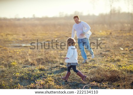 Happy family: young father with his little children walking in the field in summer morning. Strong healthy daddy playing with his daughter.