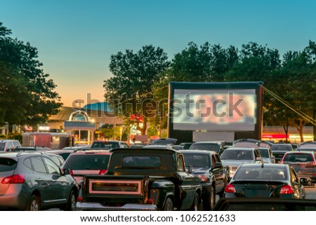 Watching movies outdoors from the car in the city parking lot on a warm summer night