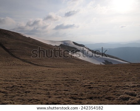 Carpathian mountains in spring. Faded grass and melting snow