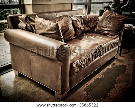 Well worn and empty leather couch in a coffee shop awaiting the next customer.