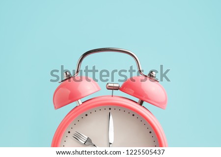 Alarm clock. Fork and knife instead of clock hands. Concept of intermittent fasting, lunchtime, diet and weight loss