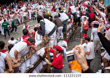 PAMPLONA, SPAIN -JULY 9: Unidentified men run from the bulls in the street Estafeta during the San Fermin festival in Pamplona, Spain on July 9, 2012.