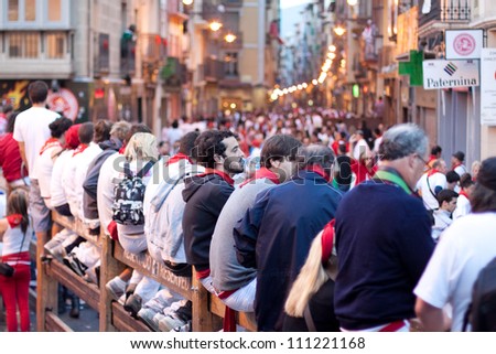 PAMPLONA, SPAIN -JULY 9: A crowd of unknown people in anticipation of beginning a run of bulls in the street Estafeta at the festival of San Fermin in Pamplona, Spain on July 9, 2012.
