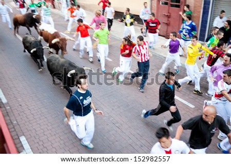 MADRID SUBURB OF SAN SEBASTIAN DE LOS REYES - SEPT. 30, 2013 : Men run from the bulls on the street of San Sebastian de los Reyes during festival, Spain 2013. Fiesta called \