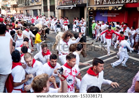 PAMPLONA, SPAIN -JULY 8: Unidentified men run from bulls in street Estafeta during San Fermin festival in Pamplona, Spain on July 8, 2013.