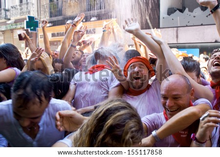 PAMPLONA, SPAIN-JULY 6: People stand under spray of water at opening of San Fermin festival. Plaza Consistorial in front of municipality. Pamplona, Navarra, Spain July 6, 2013