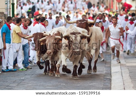 PAMPLONA, SPAIN-JULY 9: People run from bulls on street during San Fermin festival in Pamplona, Spain on July 9, 2013..