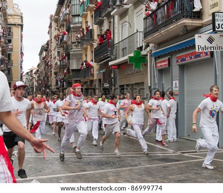 PAMPLONA, SPAIN -JULY 7: Unidentified men run from the bulls in the street Estafeta during the San Fermin festival in Pamplona, Spain on July 7, 2011.
