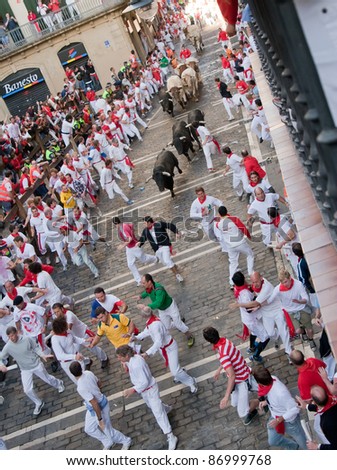 PAMPLONA, SPAIN -JULY 8: Unidentified men run from the bulls in the street Estafeta during the San Fermin festival in Pamplona, Spain on July 8, 2011.