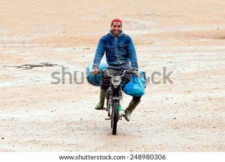 Arazane, Morocco - November 29: Village resident carries on a moped personal belongings during floods in region of Souss Massa Draa, Morocco, November 29, 2014