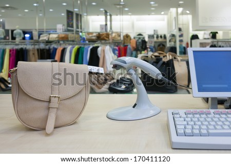 Handbad in fashion clothing store. Cashier register, scanner computer on sales counter in shop.
