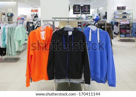Close up of sweaters, sweatshirts on retail shop rack. Store interior.