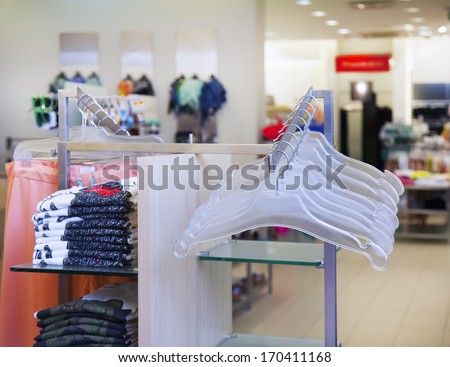 Empty hangers, rack and folded clothing in retail shop. Fashion store interior.