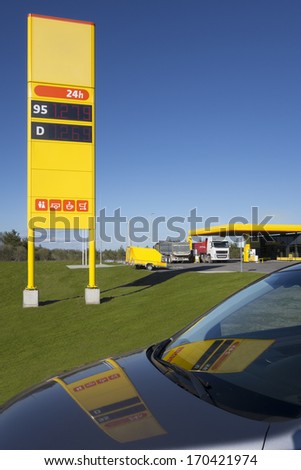 Gas, petrol station price post refection on car front window.