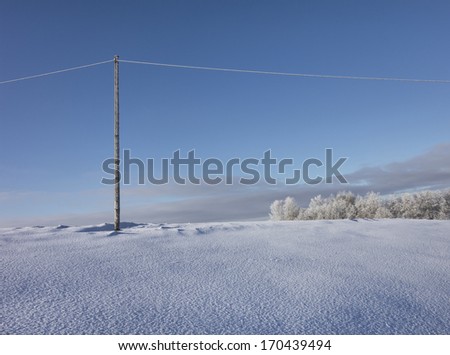 Wooden electric pole on empty snow covered landscape. Electrical industry, power line.
