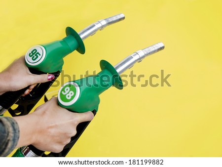 Woman`s hands holding gasoline pump. Petrol station. Nozzle. Comparison.