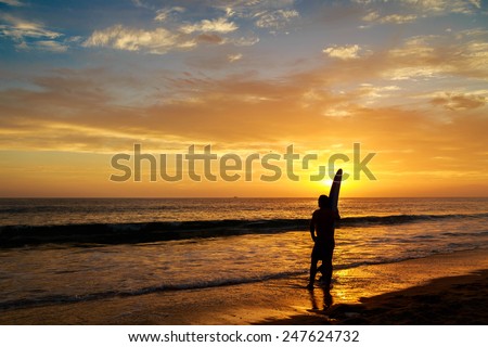 A surfer admires the last waves of the day at sunset.