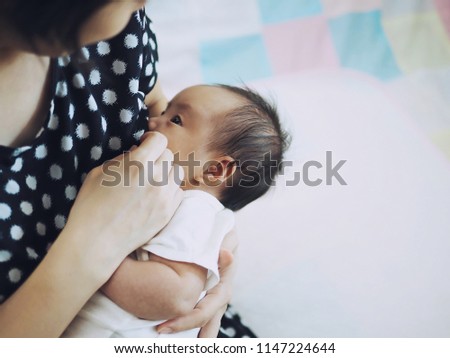 New Asian mother breastfeeding her newborn baby. Mother’s Day, Benefits of breastfeeding, Growth and development of infant children concept. (selective focus, space for text, article layout design)