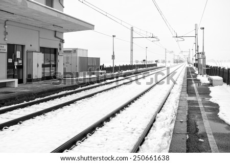 Snowing panorama with a train station, in the countryside region of Lomellina (between Lombardy and Piedmont, Northern Italy). Black and white photo