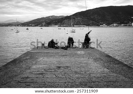 SESTRI LEVANTE, ITALY/GENOVA -?? FEBRUARY 28: three non-professional fishermen fishing from a pier of Sestri Levante marina (Genoa, Ligurian Sea), late evening. Sestri Levante (GE), February 28, 2015.