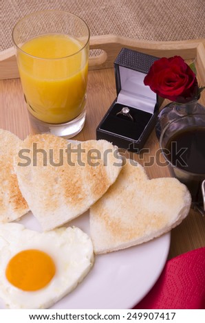 Valentines Day Breakfast on a Tray With Diamond Ring Romantic valentines day breakfast of a heart shaped egg,  heart shaped toast, a red rose orange juice and black coffee with a diamond ring.