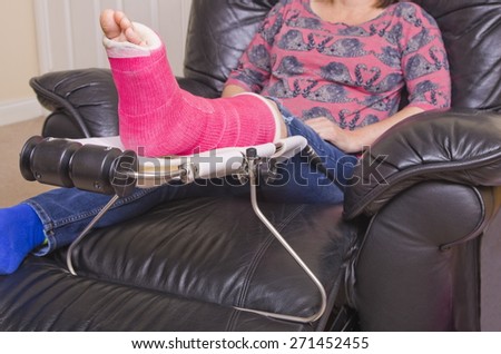 Lady with Fractured Leg\
A lady with a fractured leg sat in an armchair with her pink pot on a raised leg support