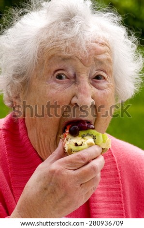 Senior Lady Eating A Waffle\
A senior lady eating a fresh cream and fruit waffle, on a summers day in the garden