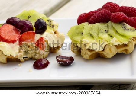 Fresh Fruit and Cream Waffles\
Two fresh summer fruit and cream waffles on a plate, one half eaten.