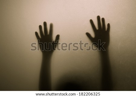 Shadow hands of child behind frosted glass