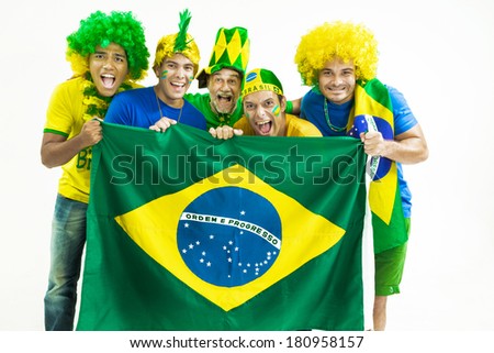 Brazilian group of happy fans dressed in green, yellow and blue, holding a Brazilian flag.