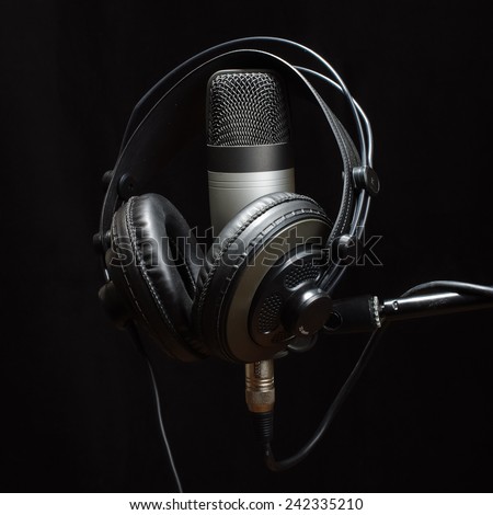 Headphones and condenser microphone isolated on the dark background