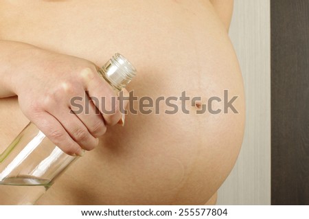 Pregnant belly and woman holding vodka bottle