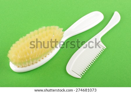 Baby hair care set of soft brush and comb isolated on the green background