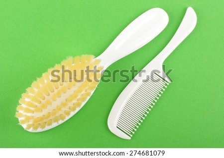 White babies hair brush and comb isolated on the green background