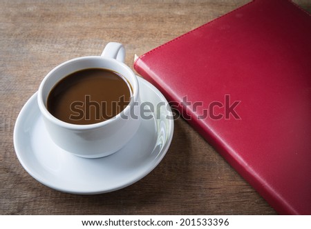 Cup of coffee, books, on table wood