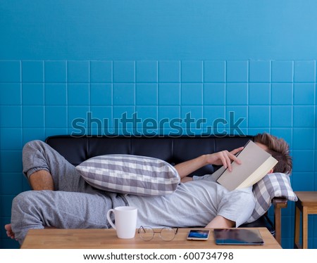 Man sleeping on old sofa with book covering his face because reading boook with preparing exam, education concept