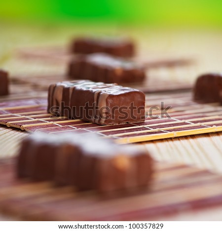 chocolates laid one on brown cloth, pastry on wooden kitchen table with green background